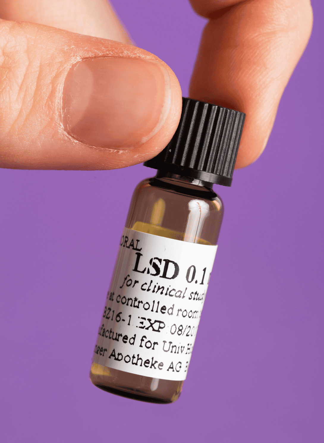 Nahaufnahme einer Hand, die ein kleines Fläschchen mit der Aufschrift „LSD“ hält.